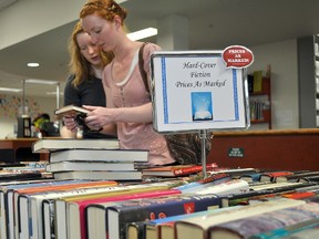Veronica, left, and Alison Loewen check out the fiction section of the Portage la Prairie Regional Library's summer book sale. (CLARISE KLASSEN/PORTAGE DAILY GRAPHIC/QMI AGENCY)