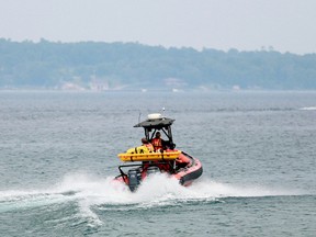 An Owen Sound Fire Department rescue Zodiac, left, speeds away from the Big Bay dock following the Islander II to the site of a float plane crash involving three Sudburians off the south end of the Griffith Island, near Wiarton, on Thursday.
