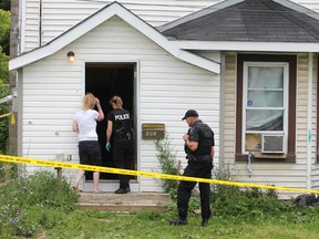 Kingston police officers talk to a woman in front of 893 Montreal St. following a stabbing at the house Friday morning.
Elliot Ferguson The Whig-Standard