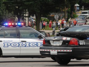 Police take one man into custody in front of a crowd of onlookers Friday night outside a residence at 197 Murray St. (JEFF DERTINGER Brantford Expositor)