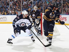 Adam Pardy #27 of the Buffalo Sabres makes a backhand pass behind the net alongside Kyle Wellwood #13 of the Winnipeg Jets as goaltender Jhonas Enroth #1 watches the play at First Niagara Center on April 22, 2013 in Buffalo, New York.