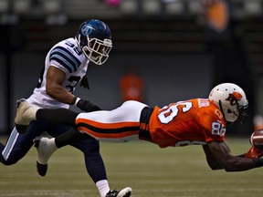 B.C. Lions wide receiver Courtney Taylor dives for a pass from quarterback Travis Lulay as Toronto Argonauts safety Matt Black moves in during the first half of Thursday's CFL football game in Vancouver. (REUTERS/Andy Clark)