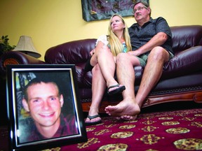 Sandra Eligh, left and her husband Larry Eligh sit together on the couch behind a photo of their late son Jason Eligh who was killed after his vehicle was struck by a truck tire in December of 2011 (THOMAS LEE/The Recorder and Times).