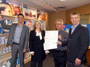 Jocelyn Turner/Daily Herald-Tribune
Grande Prairie Mayor Bill Given (left) drops a few tokens into the ‘tube-and-token’ fundraising fixture at Grande Prairie’s Medicine Shoppe on Montrose Avenue on Friday, while CMHA’s executive director for the Alberta Northwest Region Deborah Gregson accepts a cheque from owner of the local Medicine Shoppe pharmacist Curtis Crough, and president of Medicine Shoppe Canada Murray Whitby.