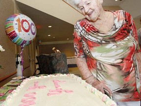 Marie Stoskopf admires her 100th birthday cake at a well-attended party at Woodland Towers in Stratford Sunday. (MIKE BEITZ, The Beacon Herald)