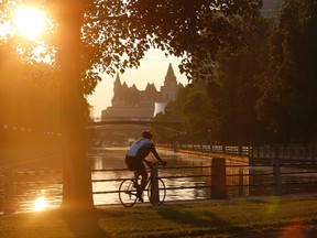 A cyclist rides at sunset along the Rideau Canal in Ottawa July 4, 2013.   REUTERS/Chris Wattie       (CANADA - Tags: SOCIETY TRAVEL SPORT CYCLING)