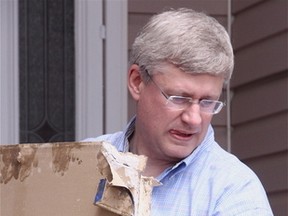 KEVIN RUSHWORTH HIGH RIVER TIMES/QMI AGENCY. Prime Minister Stephen Harper helped the Mathieson family, residents of Sunshine Meadow, Friday afternoon. He carried drywall down to the pile and was of assistance on the assembly line.