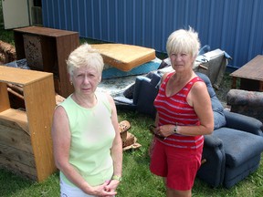 Lynn Seymour, left, and Susan Connors of the Neighbourhood Sharing Centre, with some of the illegally dumped items beside the centre. (Ian MacAlpine The Whig-Standard)
