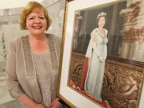 Mary Hunt chair of the Edmonton Northern Alberta Branch of the Monarchist League of Canada poses for a photo beside a portrait of Queen Elizabeth II, in Edmonton, Alta., Tuesday July 9, 2013. David Bloom/Edmonton Sun/QMI Agency