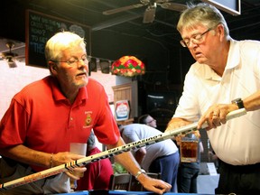 Cliff Smith, left, and John Stack, right, investigate an autographed Sarnia Steeplejacks stick from the late 1980s at a Sarnia junior hockey alumni event at Stoke's Inland Tuesday. The Sarnia Legionnaires announced the formation of an alumni association covering seven decades of junior hockey in the city. (PAUL OWEN, The Observer)