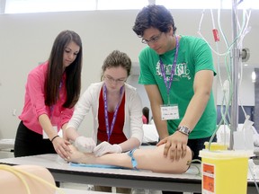 Chatham-Kent secondary school students are getting a taste of a medical career at the annual MedQUEST health career exploration program this week in Chatham, Ontario. Sarah Houle, left, assists Clarissa Priest start an intravenous drip in a practice arm while MedQUEST co-ordinator Shawn Segeren oversees the operation. VICKI GOUGH/ THE CHATHAM DAILY NEWS/ QMI AGENCY