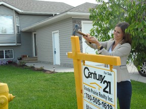 Jocelyn turner/Daily Herald-Tribune
Century 21 real estate agent Brandi Martin hammers down a for sale sign on one of the available properties on 72 Avenue Wednesday morning. The property, Martin said, is just one of the available properties that may fit into the budget of a first time home buyer.