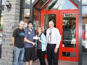 Randy Scriber, manager of North Face in Banff hands off a cheque for $1,500 to Katie Fedoration of the Banff Community Foundation for their "After the Flood Stewardship Foundation" on Wednesday, July 10, 2013. At left is store owner Cam Wilson and far right is Banff Community Foundation chair Carsten Sorensen. Russ Ullyot/ Crag & Canyon/ QMI Agency