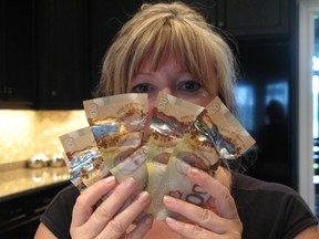 Londoner Trina Moniz clutches some of the $1,200 in plastic bank notes she says warped and melted from the heat of a common table lamp, leaving her with an up to eight-month wait for the Bank of Canada to replace the bills. BRENT BOLES / THE LONDON FREE PRESS / QMI AGENCY