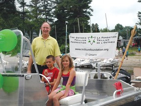 MPP John Yakabuski poses with Cole Jefferson and Evelyn Lorenzen on the Deep River Yacht and Tennis Club’s newest boat, which they received the money to purchase from a grant from the Ontario Trillium Foundation.