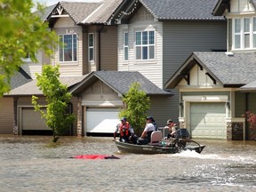 RCMP and Fish and Wildlife officers go past a submerged car as they patrol the still-flooded Hampton Hills area in High River, Alberta, on July 4, 2013. (Mike Drew/Calgary Sun/QMI AGENCY)