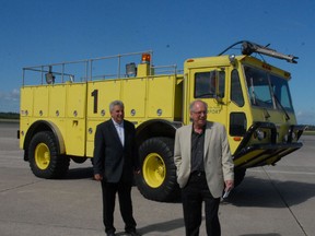 Bryan Hayes, Sault Ste. Marie MPP (left), and Jerry Dolcetti, chair of Sault Ste. Marie Airport Development Corp., walk past an old fire truck used since 1987.