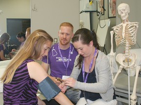 Medical student Dave Schulz oversees as Chelsea Fleury, left, has her blood pressure taken by Courtney Roberts.