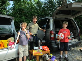 Samuel (left), Greg and their dad Dave Strachan prepare items for a trunk sale at Waterford United Church being held July 20 to raise money to send hockey equipment to Attawapiskat, Ontario. (CAROL STEEDMAN For The Expositor)