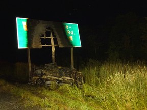 A burnt out highway sign stands above the van that left Highway 401 eastbound lanes just west of the Wallbridge Loyalist Road off ramp Saturday around midnight. One man died as a result of the single-vehicle collision and and 18-year-old male has been charge with impaired driving causing death.