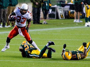 BC Lions Andrew Harris bowls over Edmonton Eskimos Joe Burnett (22) and T.J. Hill  during second half CFL action at Commonwealth Stadium in Edmonton, Alta. on  Saturday, July 13, 2013. The Eskimos lost 17-3. Amber Bracken/Edmonton