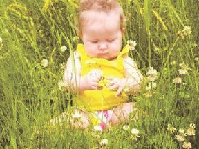 Tenley Cloke, 9.5 months, examines flowers while on vacation at Long Island Lake.