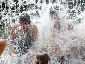 Tracy Mallory, left, and Ed Gosselin cool off in a wall of water at the Forks of the Thames spray pad in downtown London Monday afternoon, with the Humidex making the day’s high of 31 C feel more like 42 C. The Middlesex-London Health Unit issued its second heat alert of the summer, expected to stay in effect until at least Thursday with temperatures forecast between 30 C and 32 C for the rest of the week.
(CRAIG GLOVER, The London Free Press)