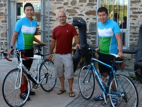 Brothers Soohyung (left) and Soojeong (right) Choe who are biking across Canada to raise money for Azheimer’s Disease research, pose with Hardwear Company owner Steve Strachan, who gave them free bike tune-ups at his shop. 
ALAN S. HALE/Daily Miner and News