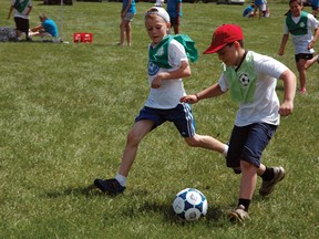 Aaron Moore (right) runs down the field with the ball as Luis Sjaarda (left) tries to get it from him at Calvary Baptist's 10th annual soccer camp.