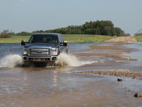 A truck attempts to navigate a partially submerged road.