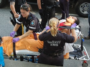 Paramedics treat a young man who was attacked by three suspects armed with baseball bats on Evergreen Street.