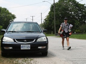 Canada Post letter carrier Shari Cloutier walks the Scollard Street route, Wednesday, where pedestrians have to walk onto the street to avoid cars parked on the side.