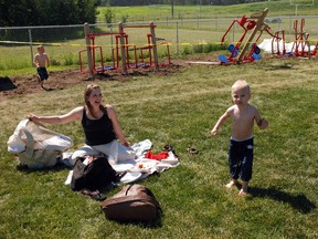 The installation of adult exercise equipment in the Sexsmith Spray Park will be ready for use within the next 10 days. Chantelle Kennedy says she can’t wait to use the equipment while her son Marshall, 4, (right) plays at the water facility. During a ceremony Wednesday afternoon, the County of Grande Prairie handed a $15,000 cheque to the Town of Sexsmith to help replace the cement surface of the Spray Park with rubberized matting. (Caryn Ceolin/Daily Herald-Tribune)