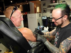 Tattoo artist Martin Bourgeois, right, works on a tattoo for Mark Lucas at the Twisted Doll in Sudbury, ON. on Wednesday, July 17, 2013. JOHN LAPPA/THE SUDBURY STAR/QMI AGENCY