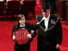 Senate page Brigette DePape, holding a sign reading "Stop Harper" is led from the room as Canada's Governor General David Johnston delivers the Speech from the Throne in the Senate chamber on Parliament Hill in Ottawa June 3, 2011.  REUTERS/Chris Wattie