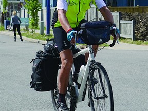 Joachim Ostertag rides his bike along a road in south Edmonton on Sunday, July 14. Ostertag is riding from Owen Sound, Ont. to Vancouver in an effort to raise awareness for violence against women. Steven Wagers/Sherwood Park News/QMI Agency