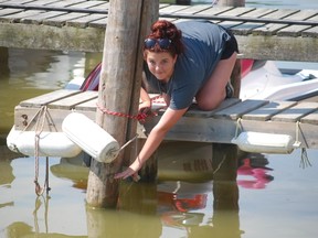 Courtney Atherton, an employee at Stan’s Marina in Port Stanley, holds a hand where she said water levels should be at this time of year — about 30.5 centimetres (one foot) higher. (Ben Forrest, QMI Agency)