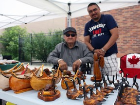 A number of First Nations-themed information booths, activities and crafts were available at the Urban Park on Wednesday, including a variety of wood carvings by Samuel Koosees Sr., left, who was joined by his son-in-law James Sutherland.