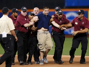 Dylan McCue-Masone is taken away by security personnel after running onto the field during Major League Baseball's All-Star Game in New York, July 16, 2013. (REUTERS/Mike Segar)