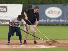 London Majors co-owners Roop Chanderdat, left, and Scott Dart rake dry fill around second base during rain delay after heavy storms flooded the infield during their Intercounty baseball game against the Kitchener Panthers on Friday night. (CRAIG GLOVER, The London Free Press)