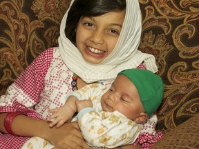 Nine-year-old Alysha Rasool, who has been fasting throughout Ramadan, holds her six-week-old brother, Ali. MARY KATHERINE KEOWN/FOR THE SUDBURY STAR/QMI AGENCY