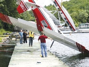 A recovery crew (right) pulls a float-equipped Citabria from Trout Lake. The airplane was damaged when high winds flipped it over at the North Bay Water Aerodrome.