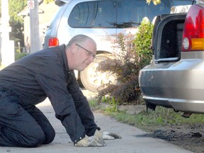 Fire inspector Dan Fraser checks damage to a car at 169 Dennis St. in Sault Ste. Marie, Ont., on Sunday, July 21, 2013.