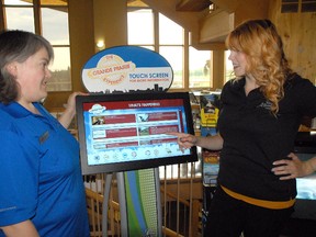 Maryann French (left) and Sara Pomeroy, employees at Centre 2000 with Travel Alberta, go through the different features of the centre's information kiosk. The kiosk is a touch screen and carries the same information as is available in various information pamphlets but is all at your finger tips in one location.  JOCELYN TURNER /DAILY HERALD-TRIBUNE