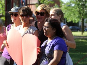 Friends pose with a large cardboard heart in McBurney Park in support of a couple who had been threatened by a series of homophobic letters in Kingston last week. (Danielle VandenBrink/The Whig-Standard)