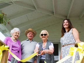 Shirley and Les Case smile as Linda Monroe cuts the opening ceremony ribbon at Case House on July 20 at the Fort la Reine Museum. With them is museum curator Tracey Turner who worked hard at fundraising to renovate the home. (Svjetlana Mlinarevic/Portage Daily Graphic/QMI Agency)