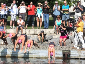 Friends, family and supporters watch as swimmers Mona Sharari, left, Samantha Whiteside, Colleen Shields, Nicole Mallette and Rebekah Boscariol dive into Confederation Basin Tuesday morning to begin their five-day swim from Kingston to Burlington.
Michael Lea The Whig-Standard