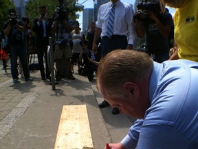 Mayor Rob Ford painted a small stretch of a University Ave. curb bright red as he kicked off the city's new curb painting pilot program Tuesday. (DON PEAT/Toronto Sun)