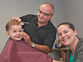 Fourteen-month-old Jakob Lanteigne sits with his mother, Laura, nearby as John Romano of Capelli Hair Design on Colborne Street gives the youngster his first haircut on Tuesday. Jakob is the fifth generation of his family to get haircuts from Romano. (Brian Thompson, The Expositor)