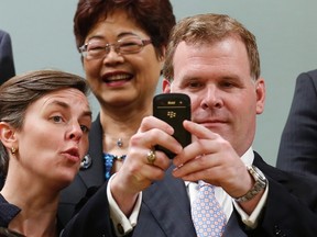 Canada’s Foreign Minister John Baird (R) takes a picture of photographers and cameramen while posing with fellow cabinet ministers during a swearing-in ceremony at Rideau Hall in Ottawa July 15. Also pictured are Minister of Labour and Minister for Status of Women Kellie Leitch (L) and Minister of State for Seniors Alice Wong. CHRIS WATTIE/REUTERS